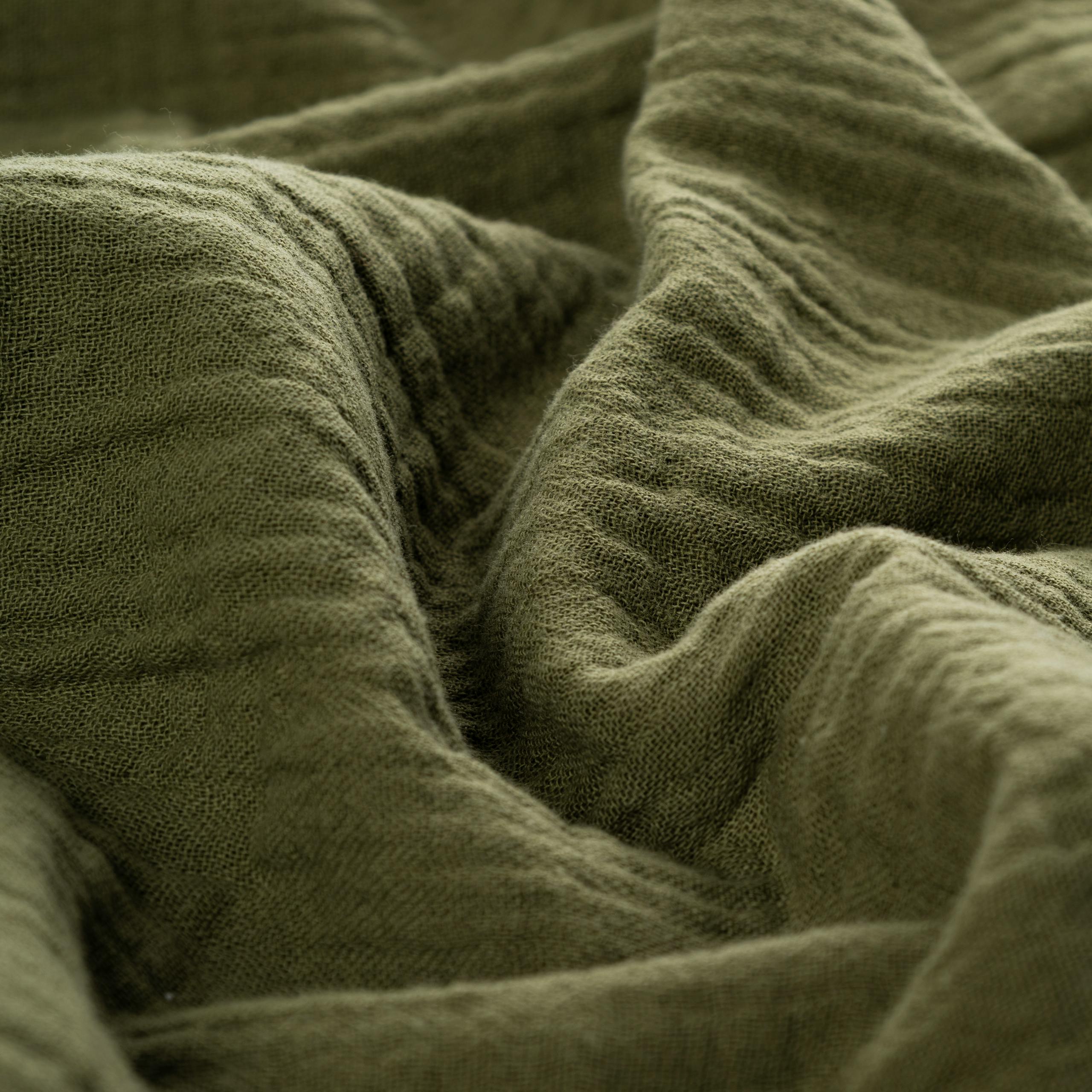 Detailed view of green crinkled cloth with soft folds and texture, ideal for backgrounds.