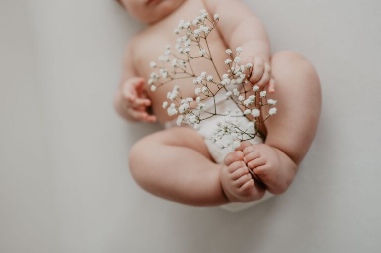 A close-up of a baby holding delicate flowers, showcasing purity and new life.