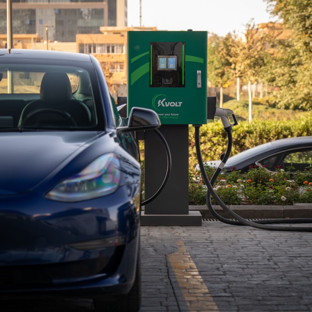 A sleek electric car charges at a modern outdoor station on a sunny day.